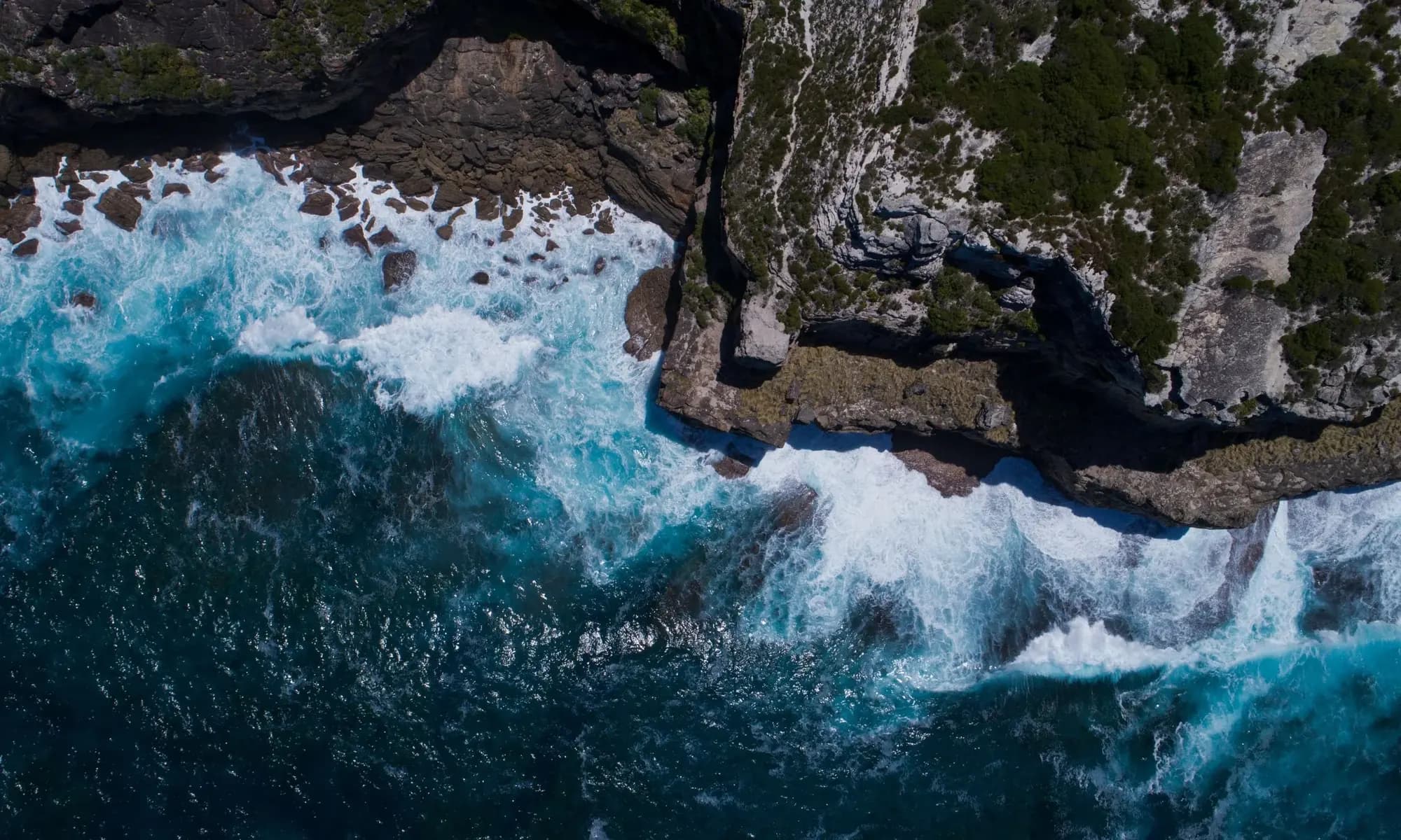 Aerial view of ocean waves breaking against coastal cliffs
